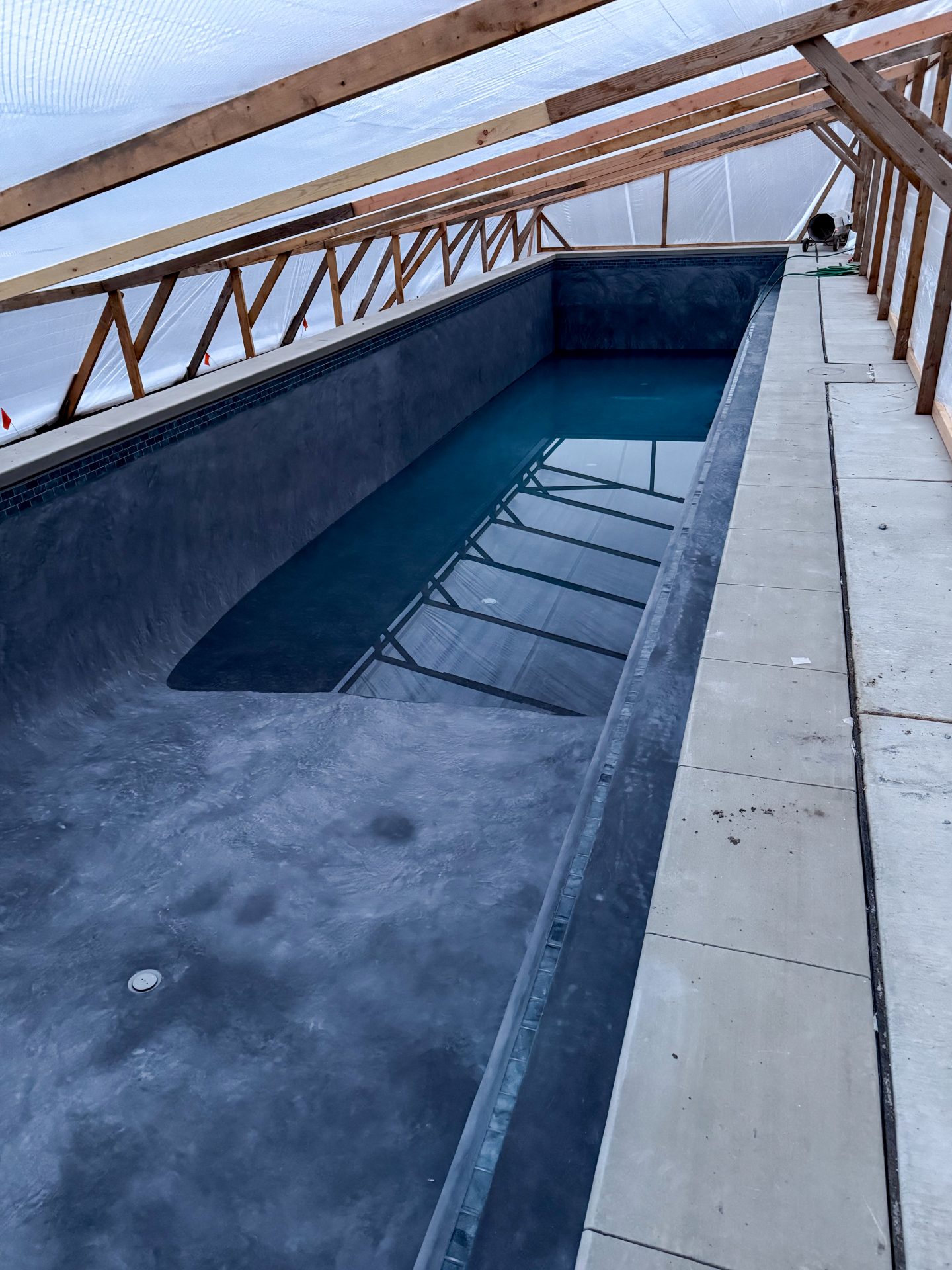 Partially filled indoor swimming pool under construction.