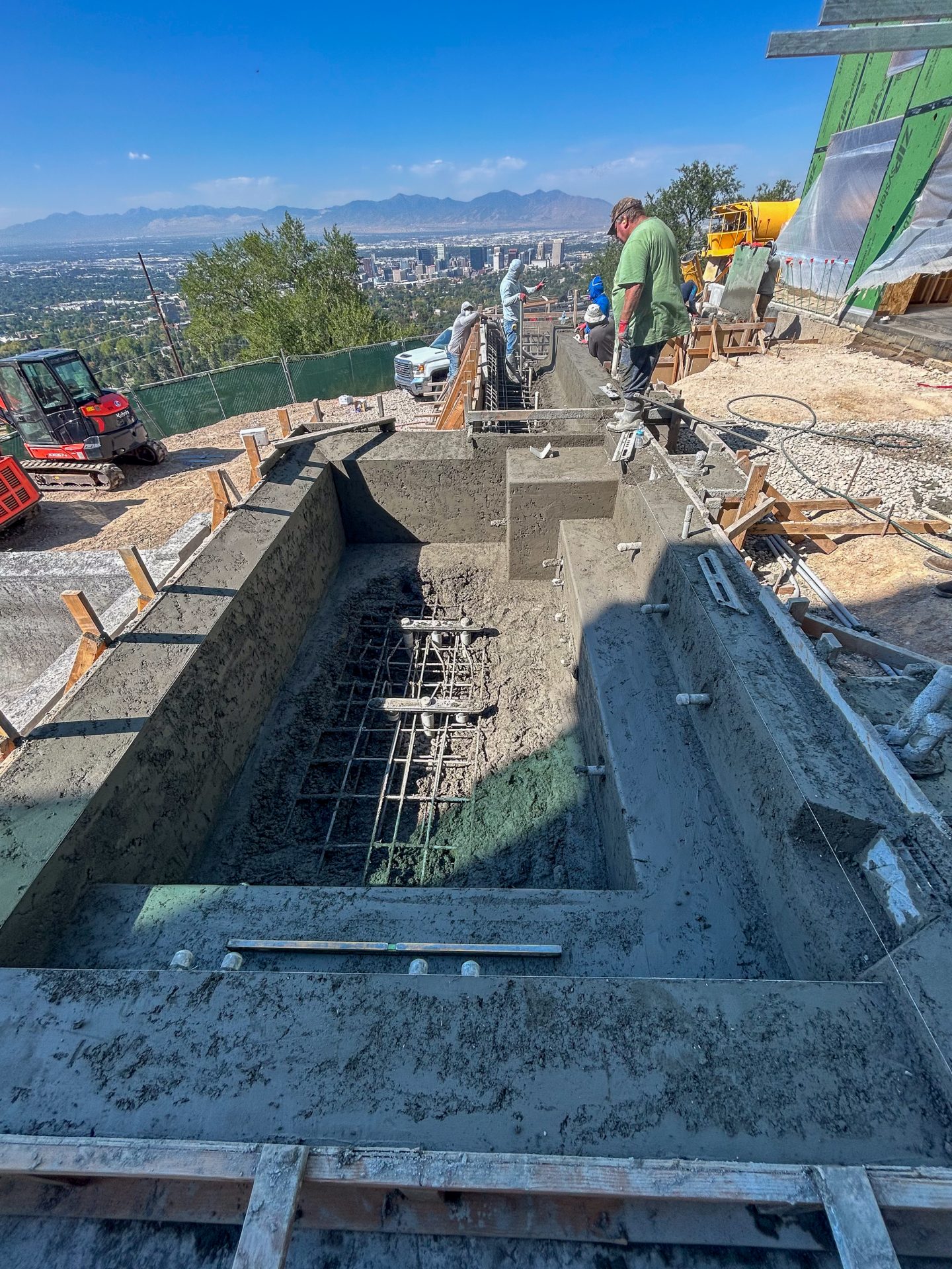 Construction workers building concrete structure with city view.