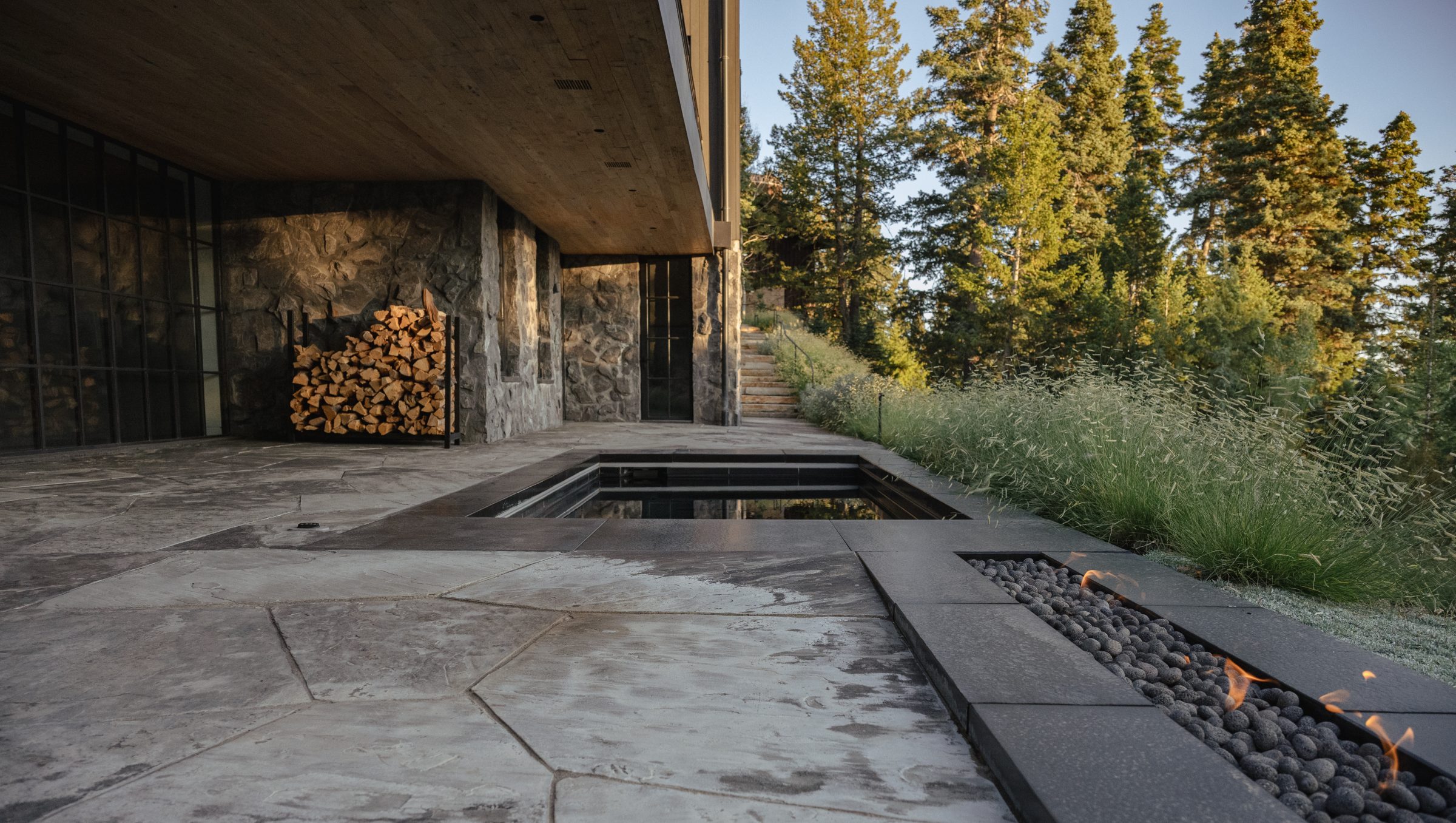 Modern patio with fire pit and stone walls.
