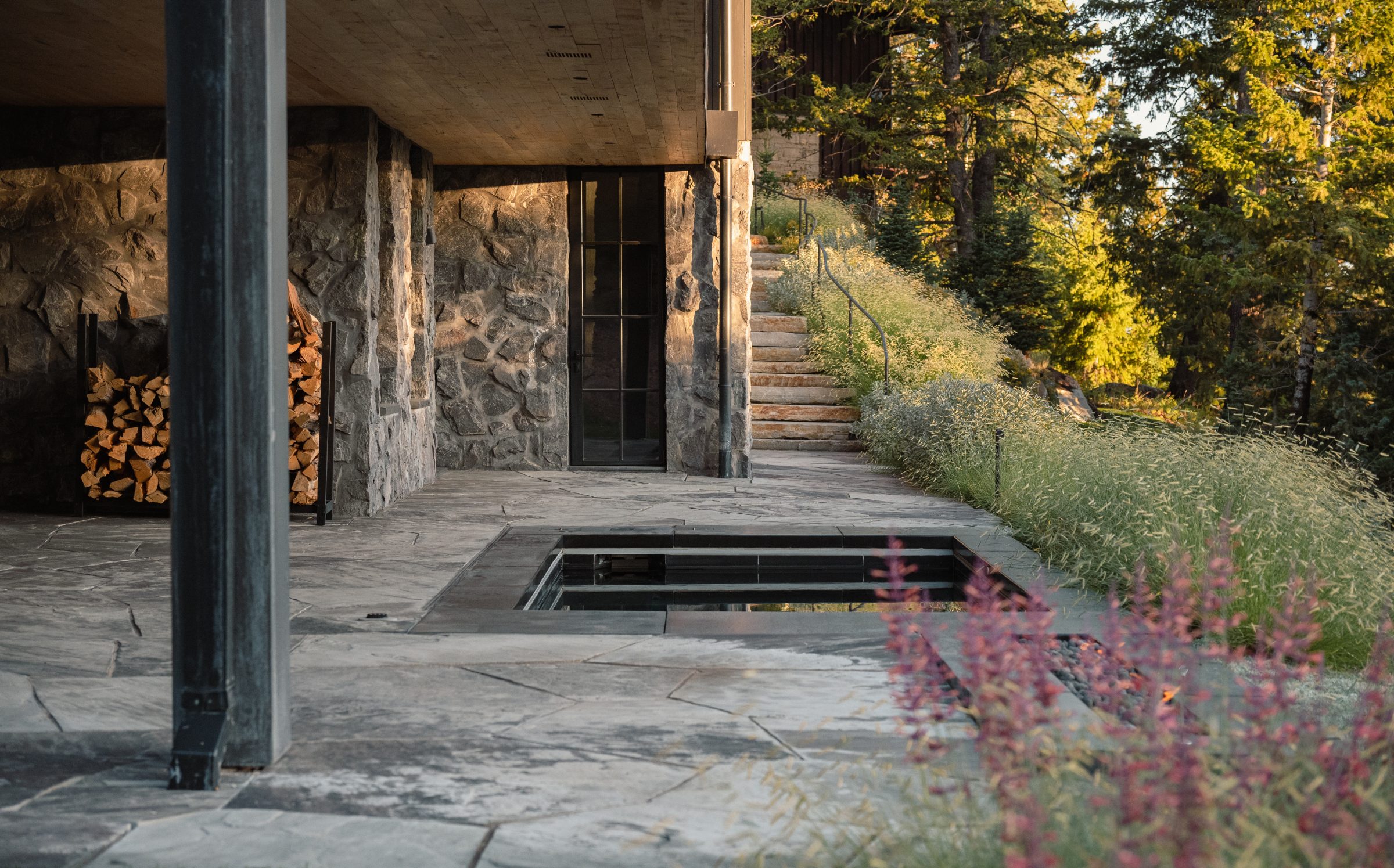 Stone patio with stack of firewood at sunset.