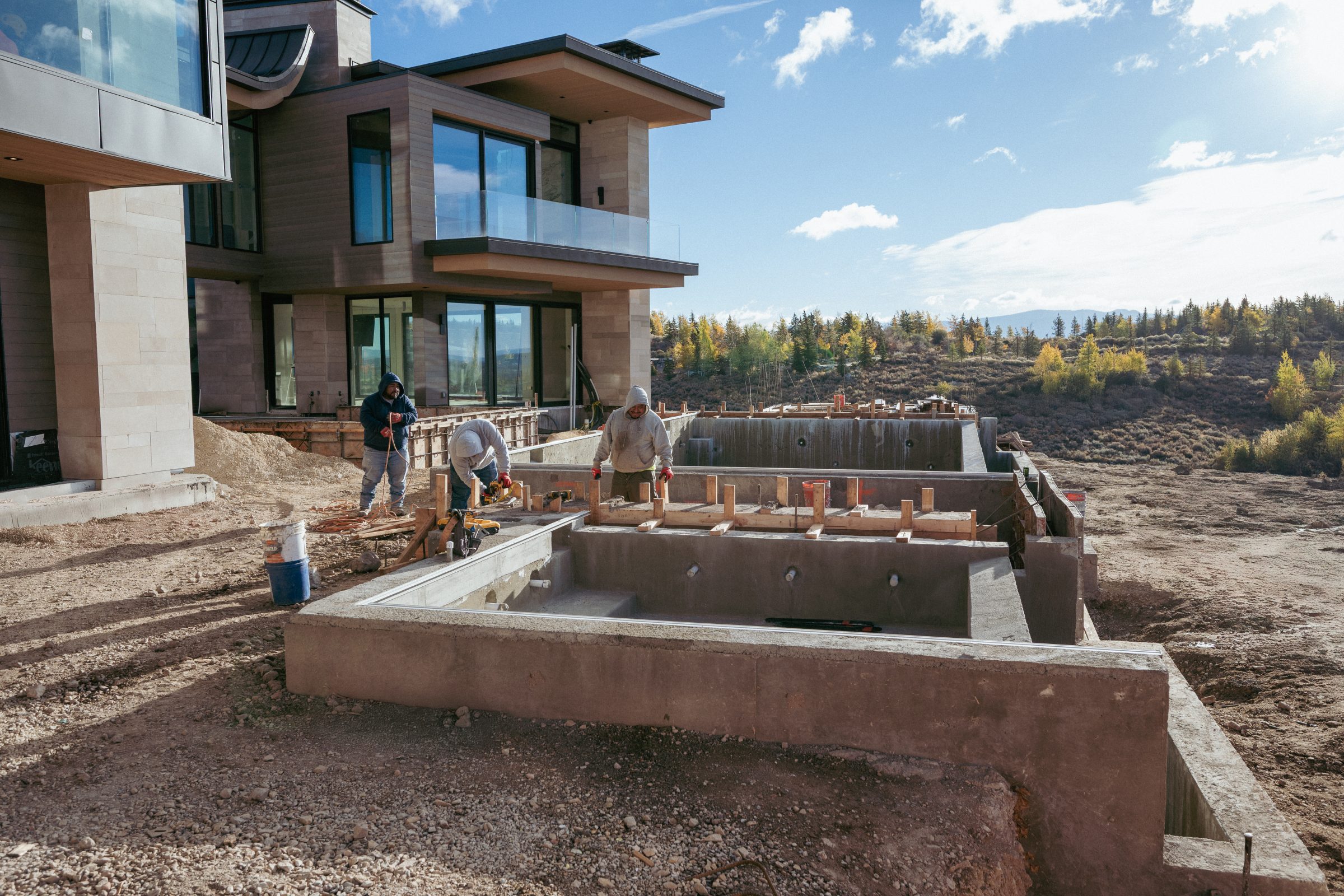 Workers constructing foundation near modern house