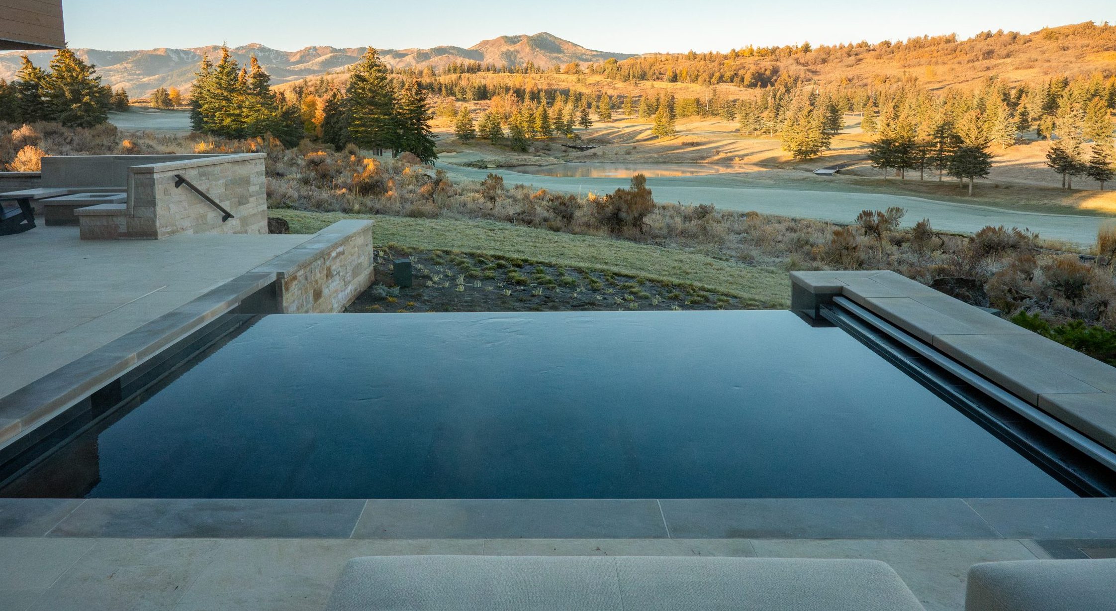 Mountain view with infinity pool and patio chairs.